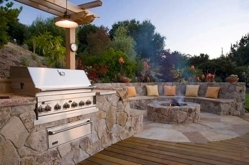 a built in grill and fire pit with seating area